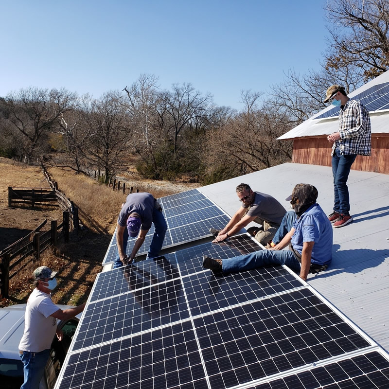 group of homeowners installing solar panels on a roof